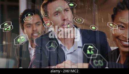 Image of eco icons and data processing over diverse business people in office Stock Photo