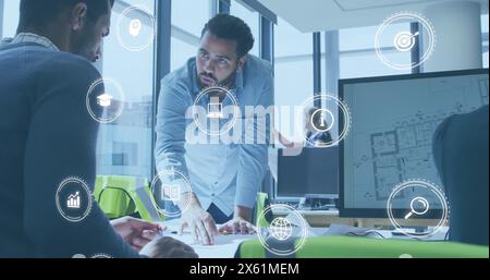 Image of icon in circles over diverse architects discussing on blueprint in office Stock Photo