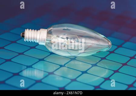 An incandescent lamp lies on a solar panel, close-up. Stock Photo