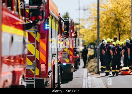 Red fire trucks in row. Teams of fire brigade on city street. Selective focus on blue flasher. Stock Photo