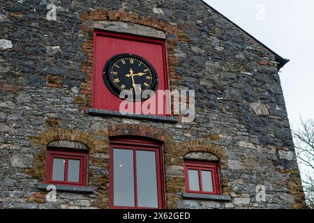Vintage clock with arrows on the wall of old stone granite house with windows Stock Photo