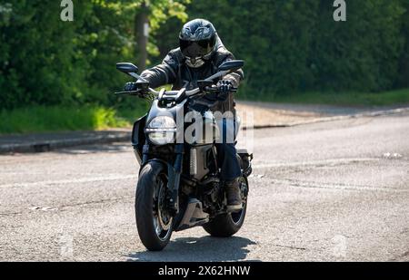 Stoke Goldington,UK - May 11th 2024: Man riding a 2011 Ducati Diavel Carbon  motorcycle on a British road Stock Photo