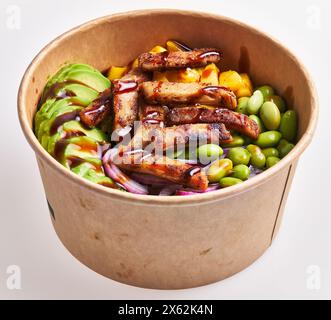 A freshly prepared poke bowl featuring succulent chicken, ripe avocado, sweet mango, edamame beans, red onion, and sauce in a paper container. Stock Photo