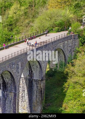 People enjoying the Spring sunshine walking and cycling the Monsal Trail over the Headstone viaduct at Monsal Head where it crosses the river Wye Stock Photo