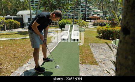 Man playing mini golf on green course during leisure activity at resort Stock Photo