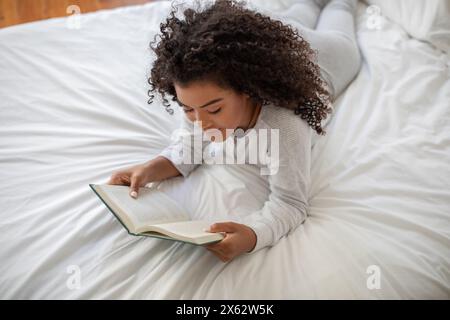 Woman Laying on Bed Reading a Book Stock Photo