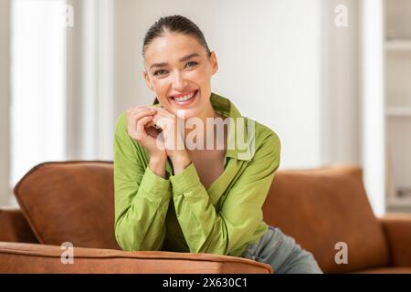 Smiling Woman Sitting on Couch at Home Stock Photo