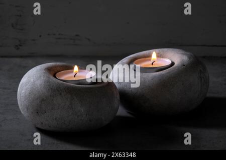 Tealights burning in concrete candle holders Stock Photo
