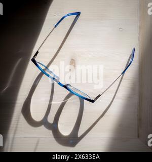 Plan view of a pair of spectacles casting shadows on a white table in strong sunlight Stock Photo