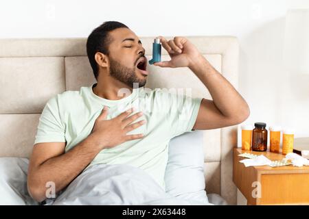 Young Man Using Asthma Inhaler While Experiencing Difficulty Breathing Stock Photo