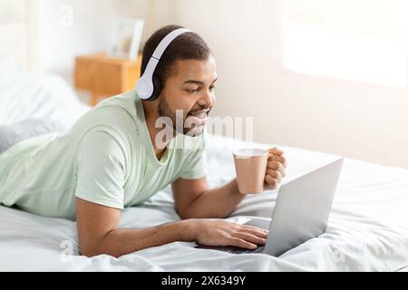 Man With Laptop and Coffee on Bed Stock Photo