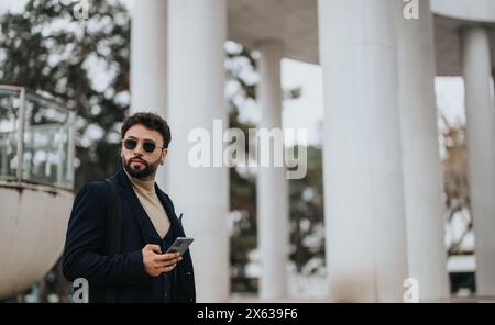 Stylish businessman using smart phone with columns in background Stock Photo