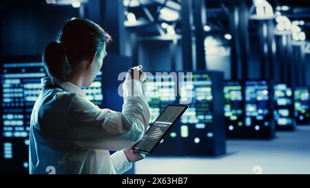 Trained asian admin running code and programming on tablet, troubleshooting and upgrading high tech facility equipment designed to accommodate servers, networking systems and storage arrays Stock Photo