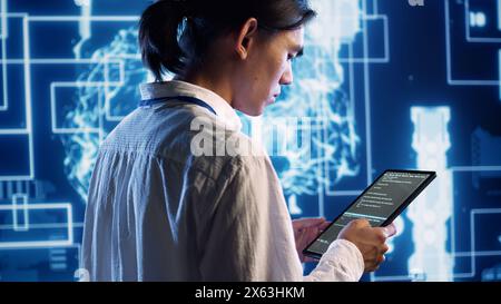 System administrator in data center running programming scripts on tablet, solving tasks. Experienced programmer manipulating lines of code for artificial intelligence applications development Stock Photo