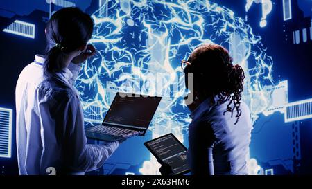 African american engineer and coworker develop artificial intelligence neural networks architecture inspired by human brain, setting up AI machine learning algorithms using programming code on laptop Stock Photo