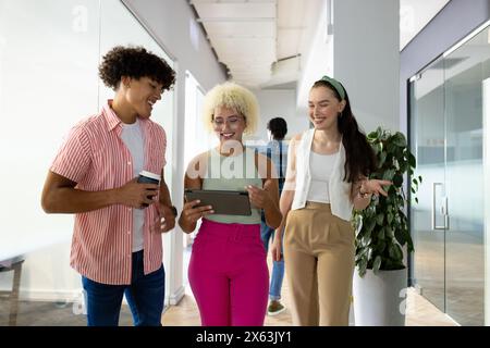 In modern office, diverse young team sharing tablet content Stock Photo