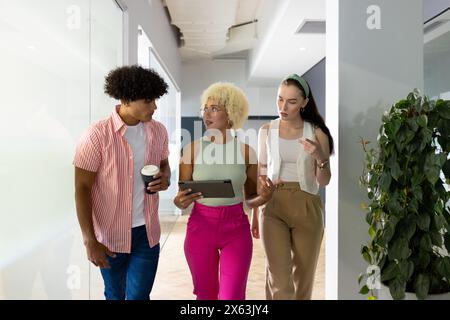 In modern office, diverse young team discussing while walking Stock Photo