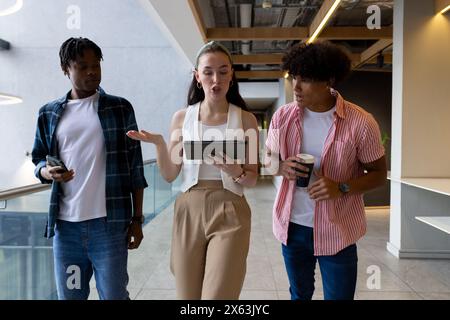 In modern office, diverse young team walking and talking Stock Photo