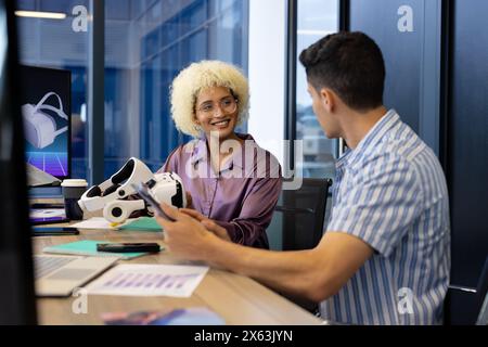 In modern office, diverse young team discussing VR technology Stock Photo