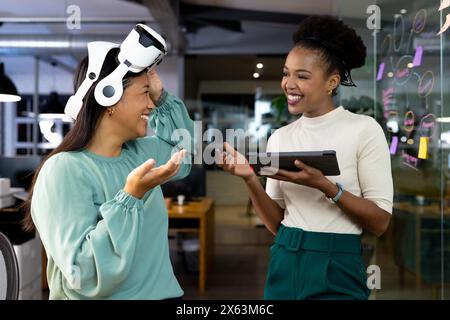At office, diverse female business colleagues laughing, working late Stock Photo