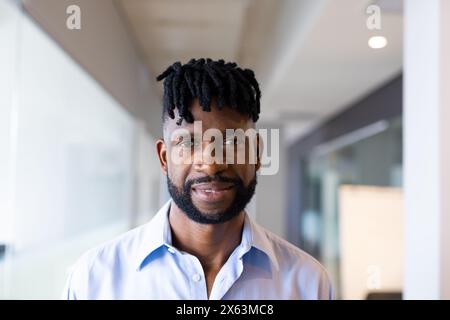 A middle-aged African American man standing at office, wearing blue shirt Stock Photo