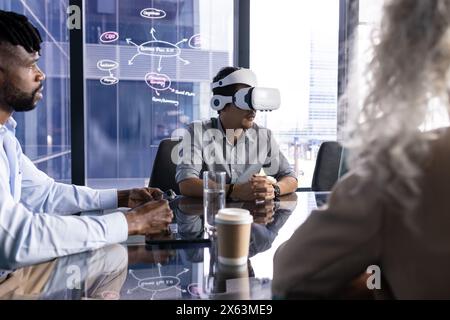At office, diverse team at table, Asian man wearing VR headset Stock Photo