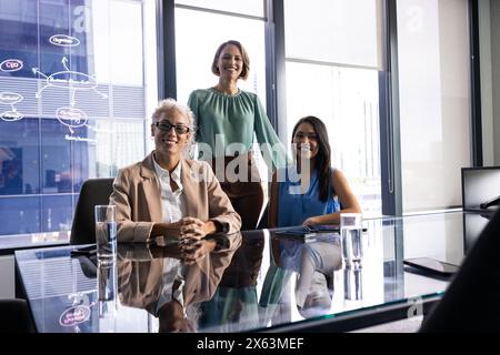 Caucasian and biracial women standing and sitting in office Stock Photo