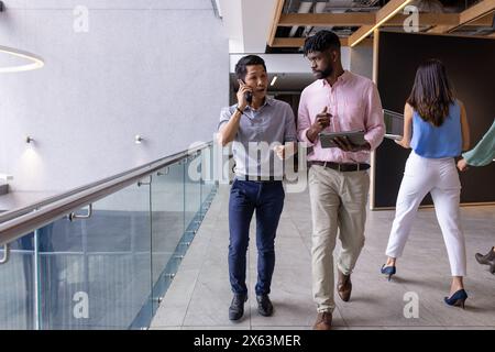 Diverse office team at office, walking and talking, wearing casual attire Stock Photo