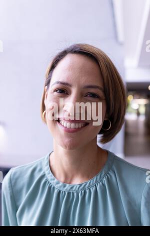 A middle-aged biracial woman at office, smiling at camera Stock Photo