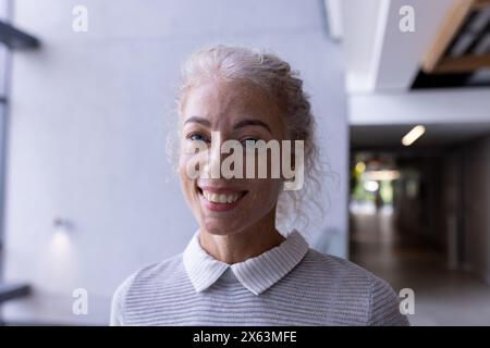 A middle-aged Caucasian female professional smiling in hallway at office Stock Photo