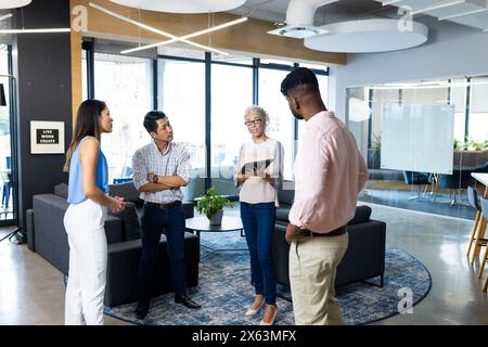 Diverse team discussing at office, holding tablets and notebooks Stock Photo