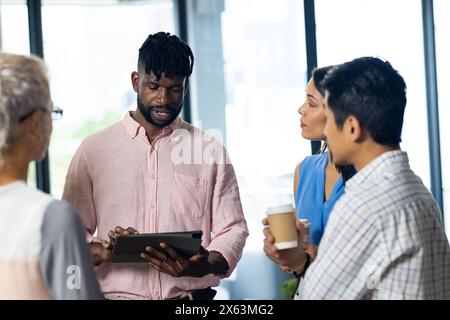 At office, diverse team discussing work using tablet Stock Photo