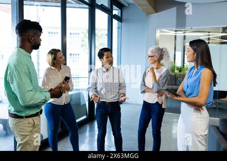 Diverse team discussing work in office, holding tablet and documents Stock Photo