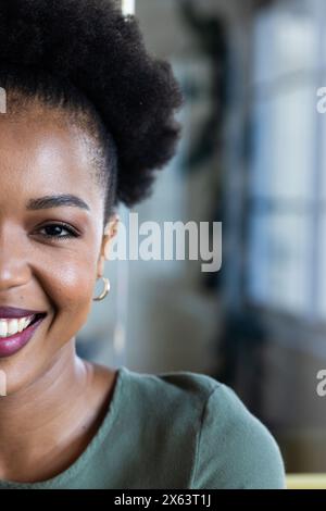 At office, African American businesswoman smiling, wearing green top, copy space Stock Photo