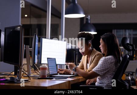 At office, diverse female business colleagues discussing work late Stock Photo