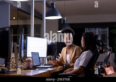 Working late, diverse female colleagues discussing work Stock Photo