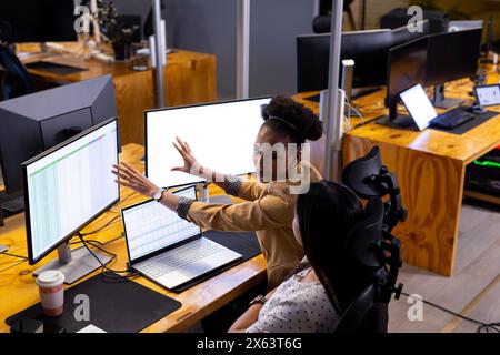 Diverse female colleagues at office discuss spreadsheets, working late Stock Photo
