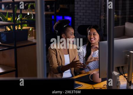 At office, diverse female business colleagues discussing, working late Stock Photo