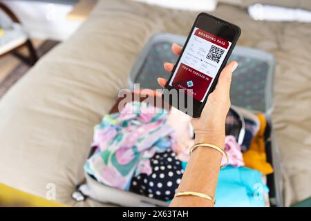 At home, mature Caucasian woman showing smartphone with a boarding pass Stock Photo