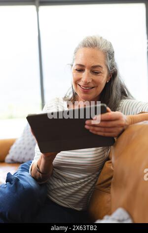 At home, mature Caucasian woman holding tablet, smiling Stock Photo