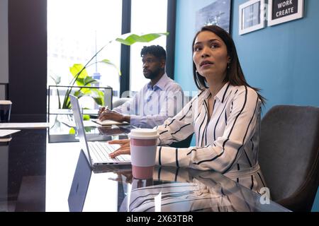 A middle-aged Black couple focusing on screens at office Stock Photo