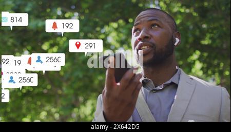 Image of notification bars over african american man talking on speaker of cellphone Stock Photo