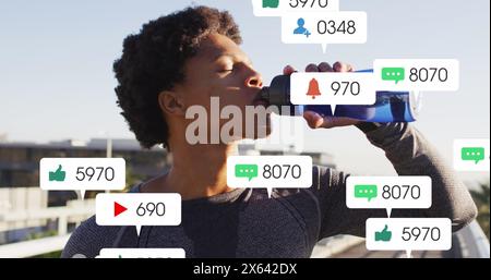 Image of notification bars, african american athlete standing and drinking water Stock Photo