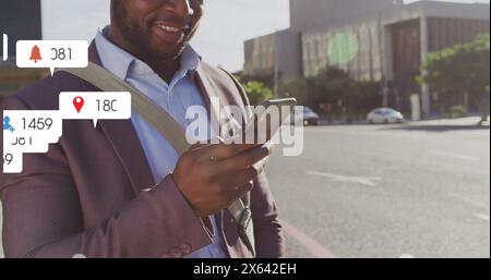 Image of multiple notification bars over smiling african american man scrolling on smartphone Stock Photo