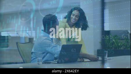 Image of graphs, loading circles, trading board, diverse coworkers discussing on desk in office Stock Photo