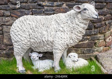 Imitation model sheep and lambs set against dry stone wall Stock Photo