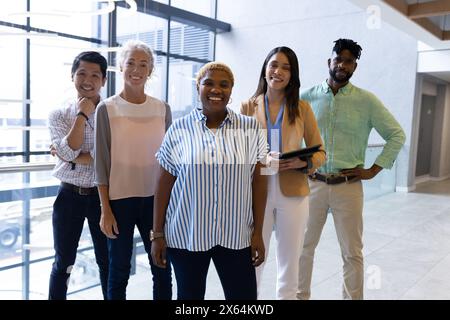 Diverse team standing together at office, smiling Stock Photo