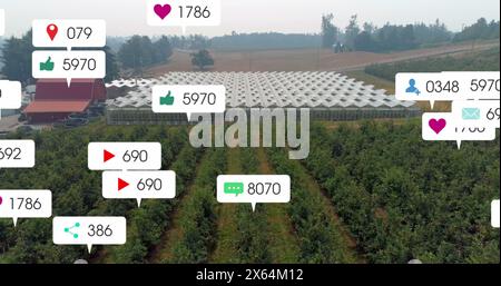 Image of social media icons floating against aerial view of solar panels in grassland Stock Photo