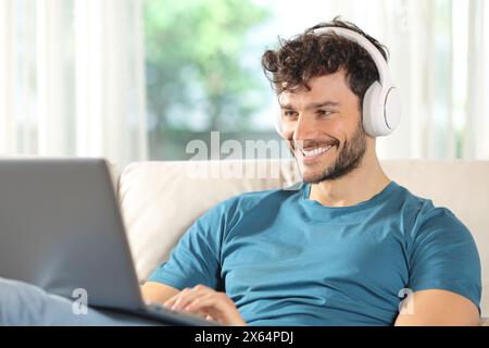 Happy man watching media on laptop sitting on a couch at home Stock Photo
