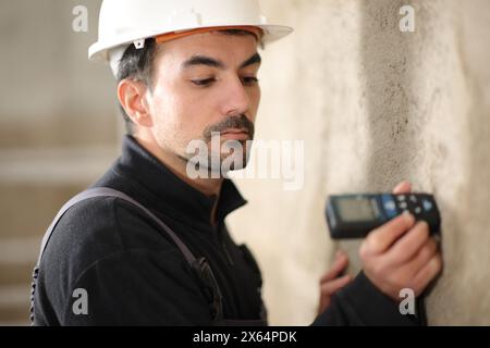 Construction worker using a digital distance meter in a wall Stock Photo